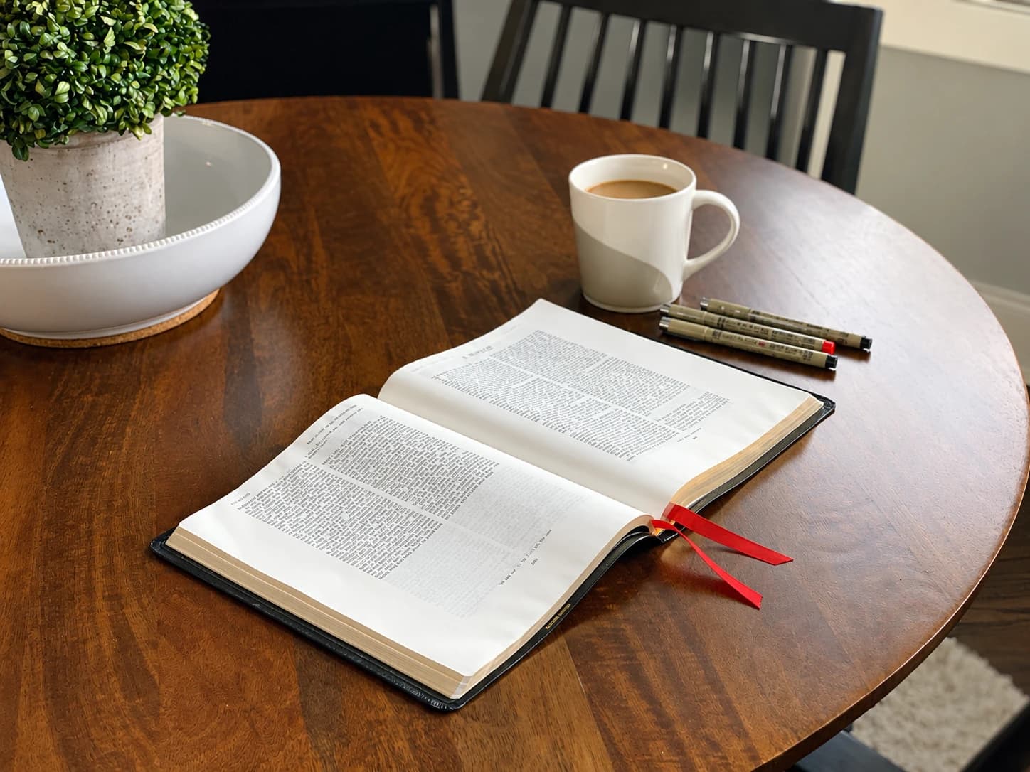 En öppen bibel och en kaffekopp på ett träbord, illustrativ bild